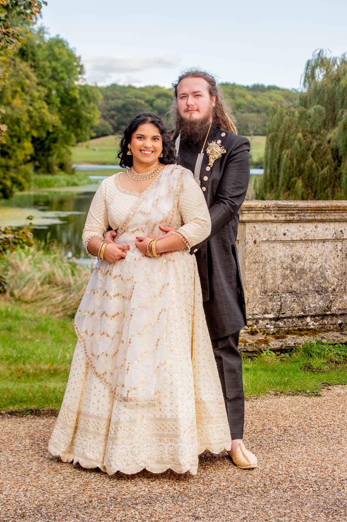 Sherni London bride and groom in fusion church wedding ceremony wearing white chikankari lucknowi lehenga and black asymmetric sherwani with gold buttons and trim