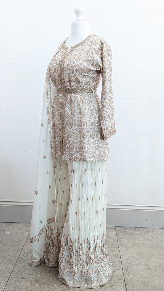 Mannequin wearing a cream jacket sharara suit set with sequins hand embroidery and threadwork long sleeves belt and dupatta